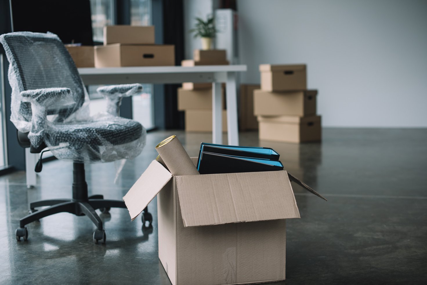 cardboard box with folders and office supplies in floor during relocation