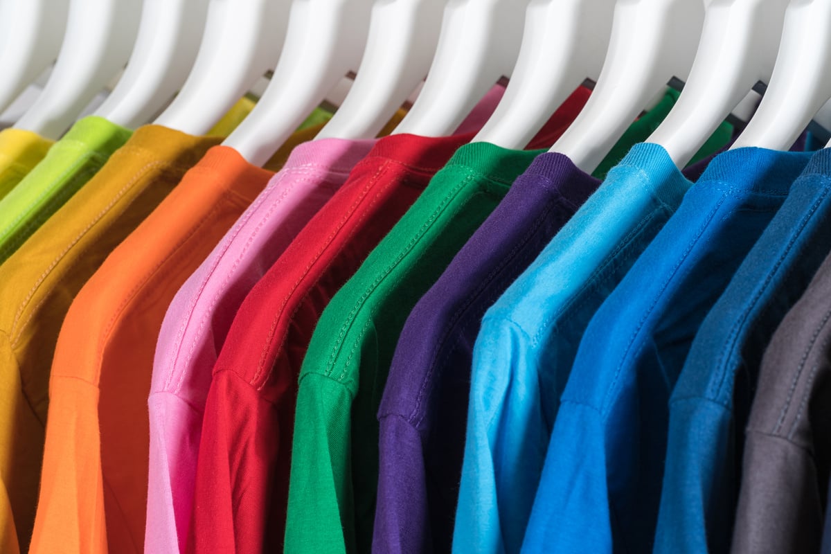 Hangers with colorful cotton t shirts in wardrobe